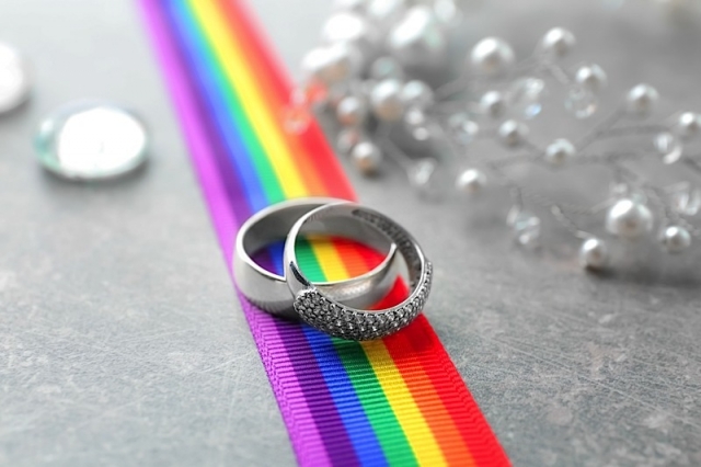 wedding rings on a rainbow ribbon, pearls scattered in the background.